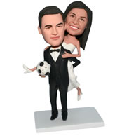 Groom in black suit handing with a soccer ball carrying bride in white wedding dress bobblehead